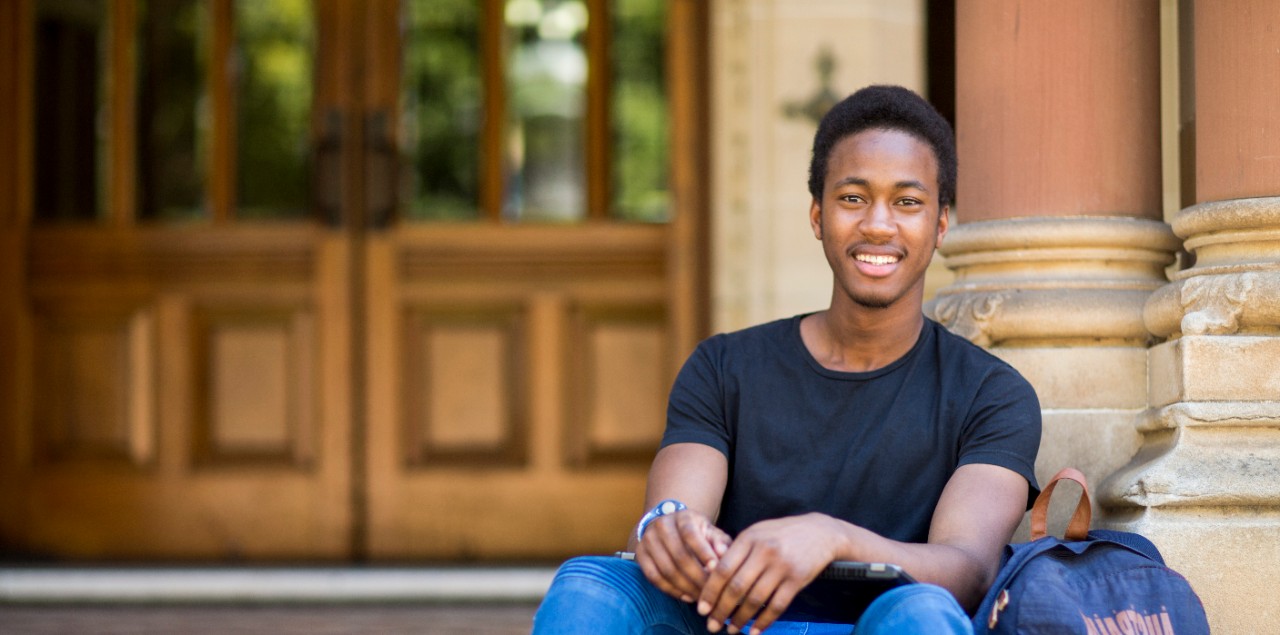 Male student smiling, sitting on Mitchell building stairs
